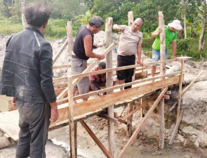 Bhabinkamtibmas Desa Unjur Membangun Jembatan di Rumah yang Dikelilingi Parit